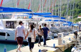 Couples walking along a jetty next to yachts